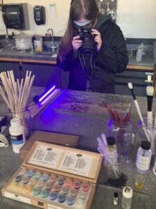 Meg Lawrence, SUNY Cortland student takes a photo of the Yvrac painting under UV-light exposure.