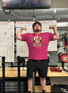 Michael in front of weight lifting stats showing muscles.